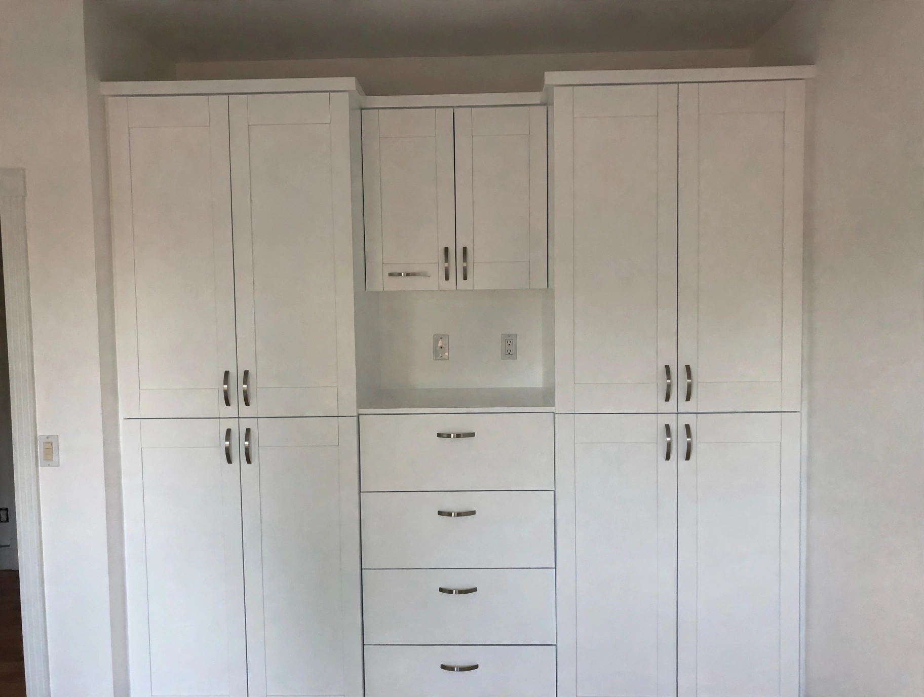 White shaker built-in wardrobe wall with drawers and brushed-nickel pulls