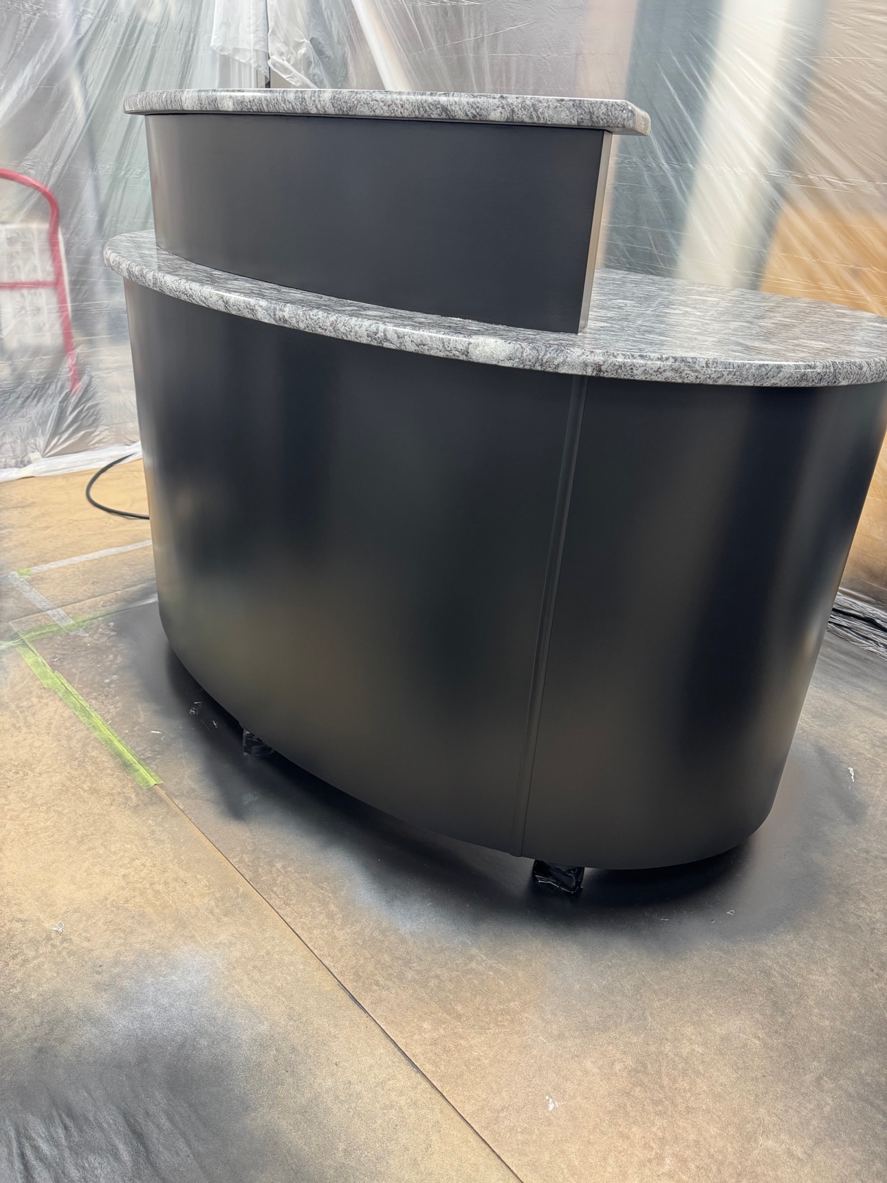 Curved reception desk refinished in matte black with granite counters